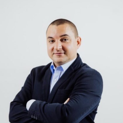 Mężczyzna w ciemnym garniturze z skrzyżowanymi rękami